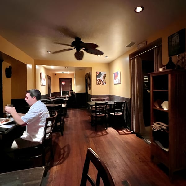 A dimly lit dining room at Muzita Abyssinian Bistro with a man seated at a table.