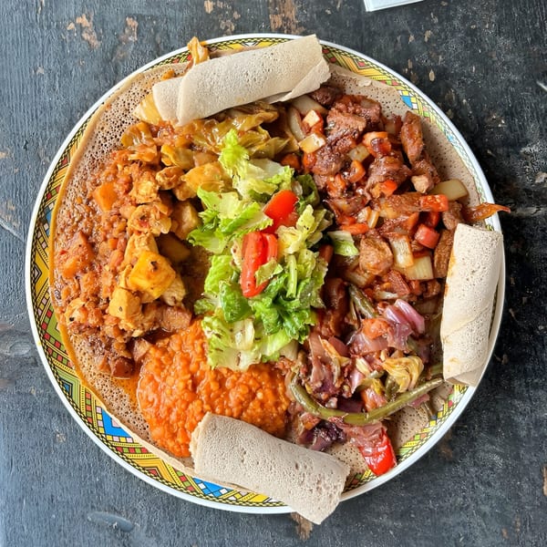 A colorful Ethiopian platter with injera bread, various stews, and a fresh salad.