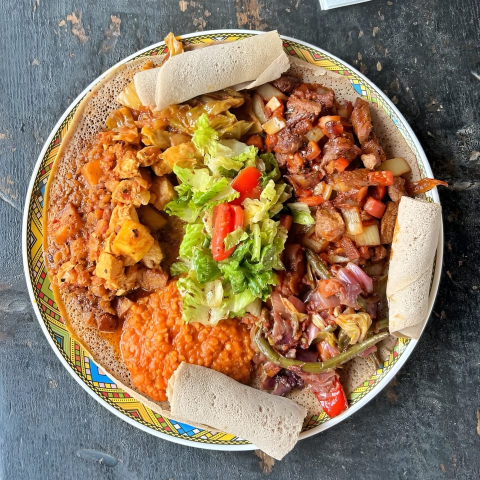 A colorful Ethiopian platter with injera bread, various stews, and a fresh salad.
