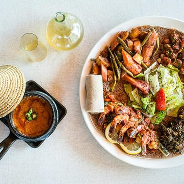 Ethiopian injera platter with various stews, vegetables, shrimp, and a side of shiro wat.