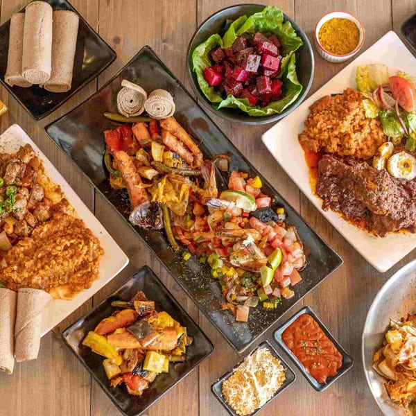 Overhead view of a variety of colorful Ethiopian dishes, including injera, stews, and salads.